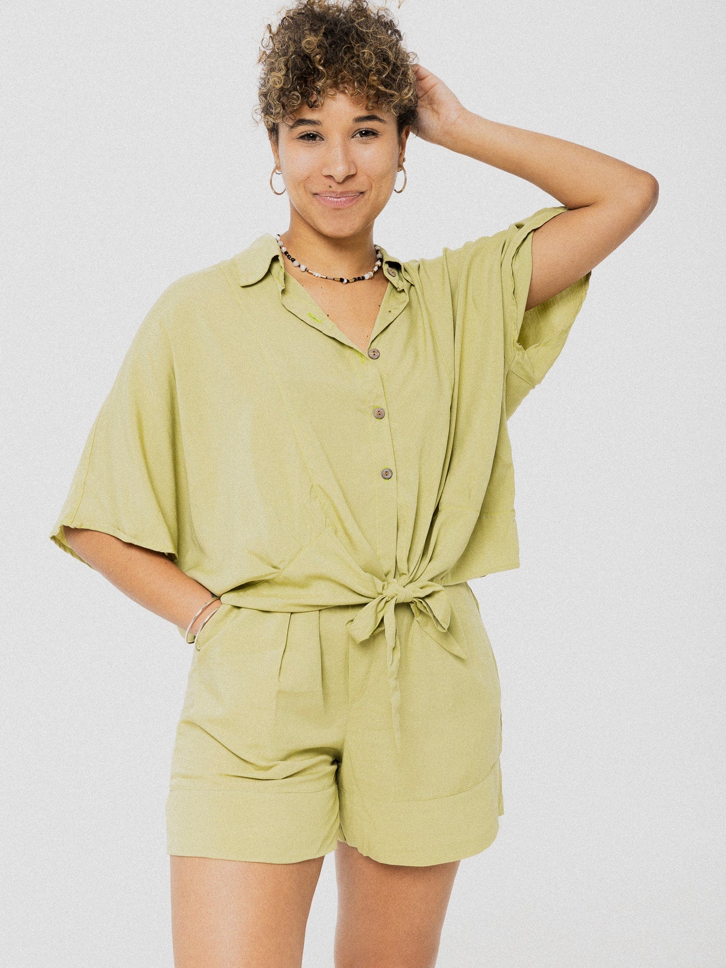 Blouse très ample verte pâle à manches courtes avec petite boucle à la fin des boutons en bas.