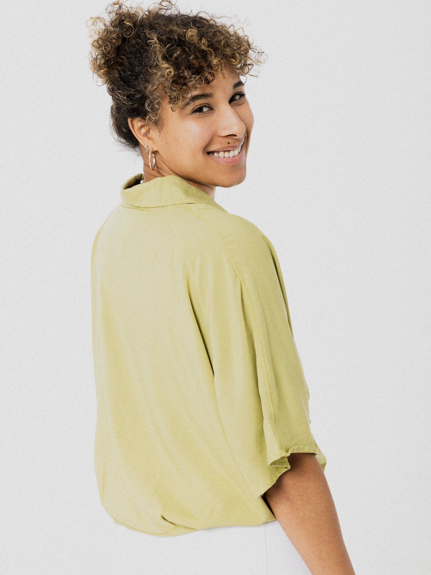 Blouse très ample verte pâle à manches courtes avec petite boucle à la fin des boutons en bas.