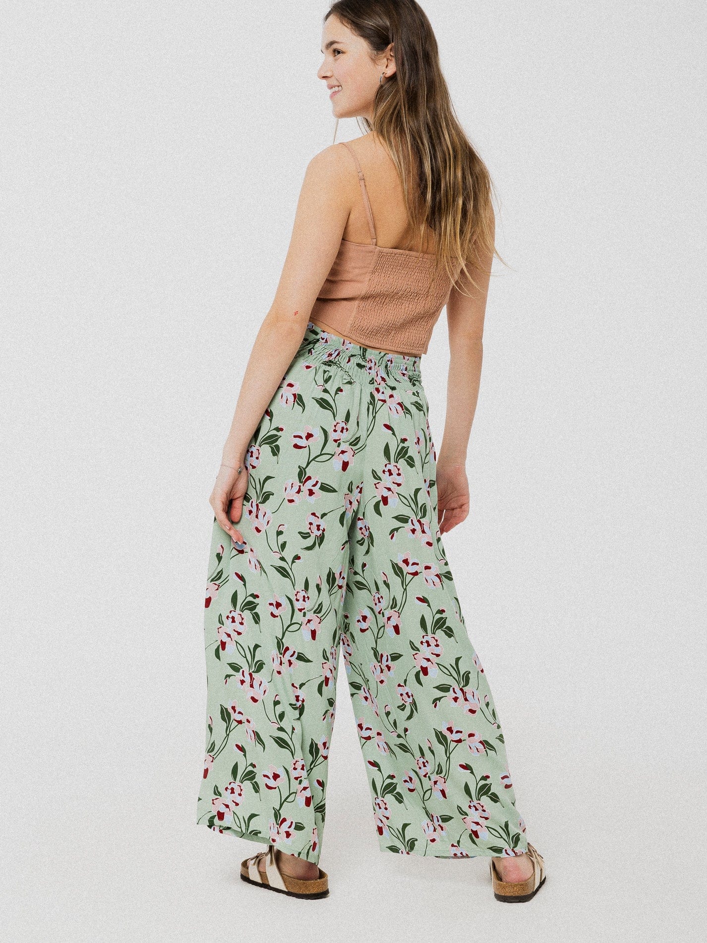 Pantalon ample et confortable vert à motif de fleur rose avec une subtile ouverture à l'avant et élastique dans le dos.