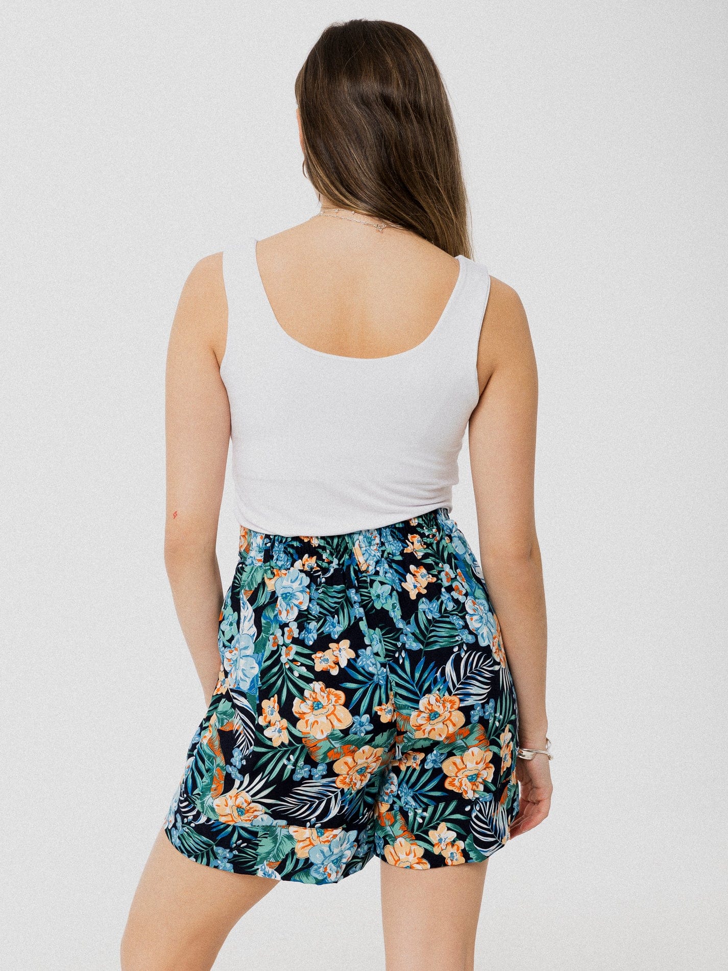 Short inoir avec motif de feuilles et fleurs tropicales orangé et marine ample, léger et confortable avec élastique au dos et poches latérales.