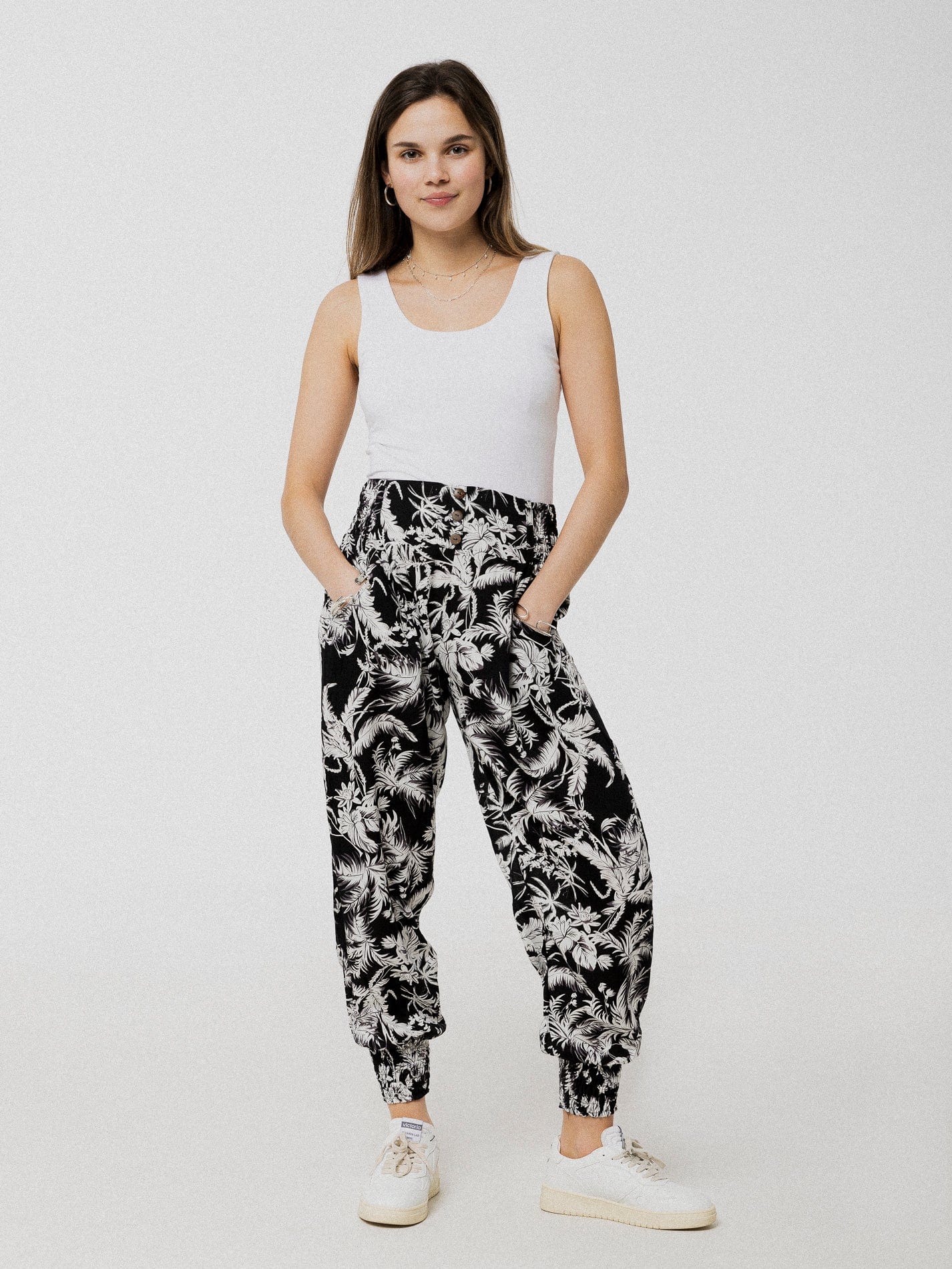 Pantalon noir à motif de feuilles blanches ample et confortable avec élastique aux chevilles et à la taille.