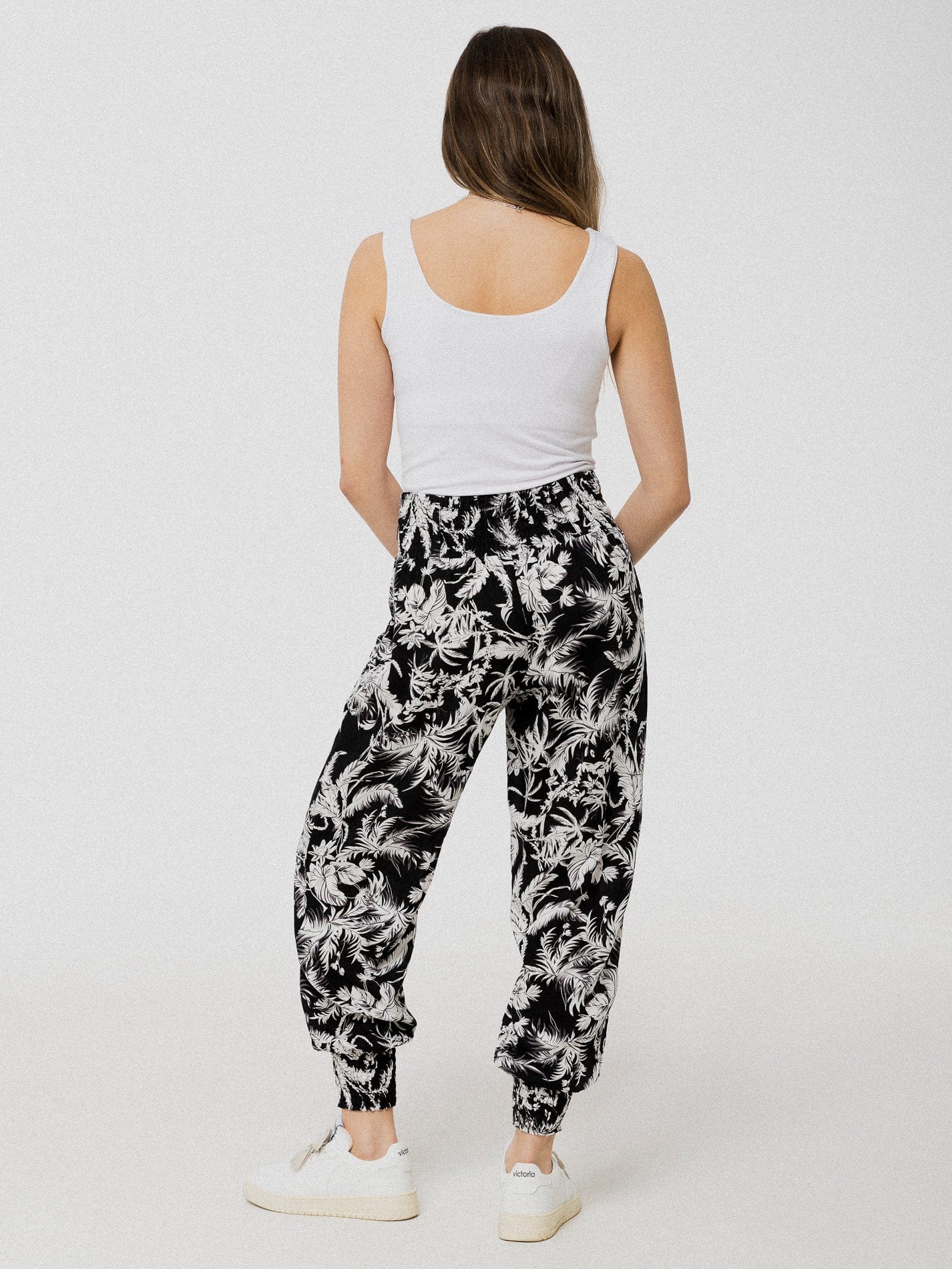 Pantalon noir à motif de feuilles blanches ample et confortable avec élastique aux chevilles et à la taille.