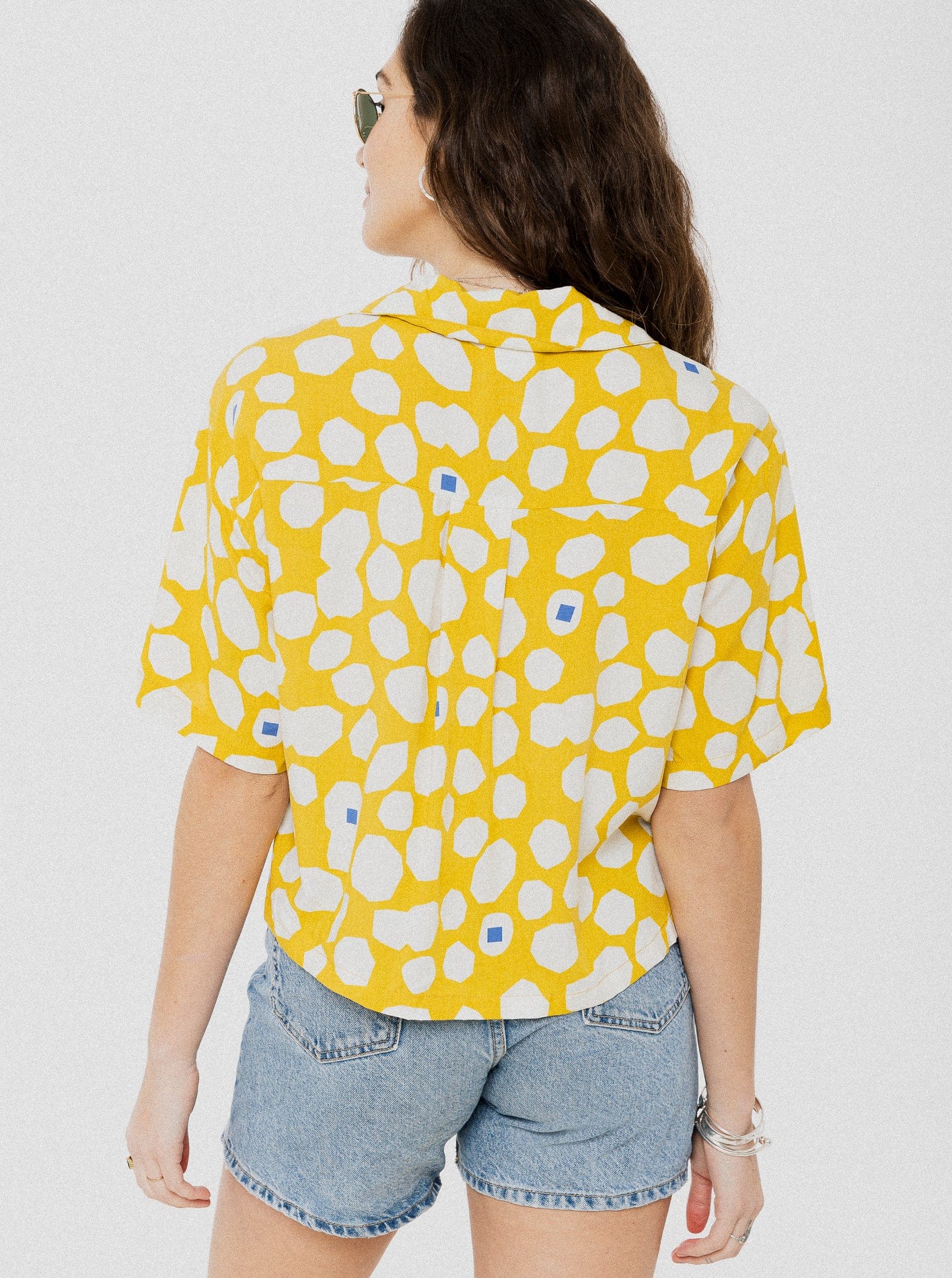 Blouse ample et confortable à manche courte jaune avec motif de ronds asymétriques blanc et quelques petits carrés bleu.